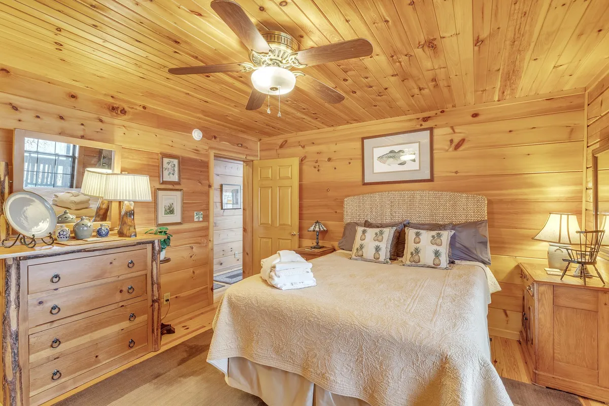 This scene displays a queen-sized bed adorned with decorative pillows, a wooden dresser, lamps on nightstands, and framed artwork. The room exudes warmth and provides a serene setting for quiet time or reading, ideal for families or couples.