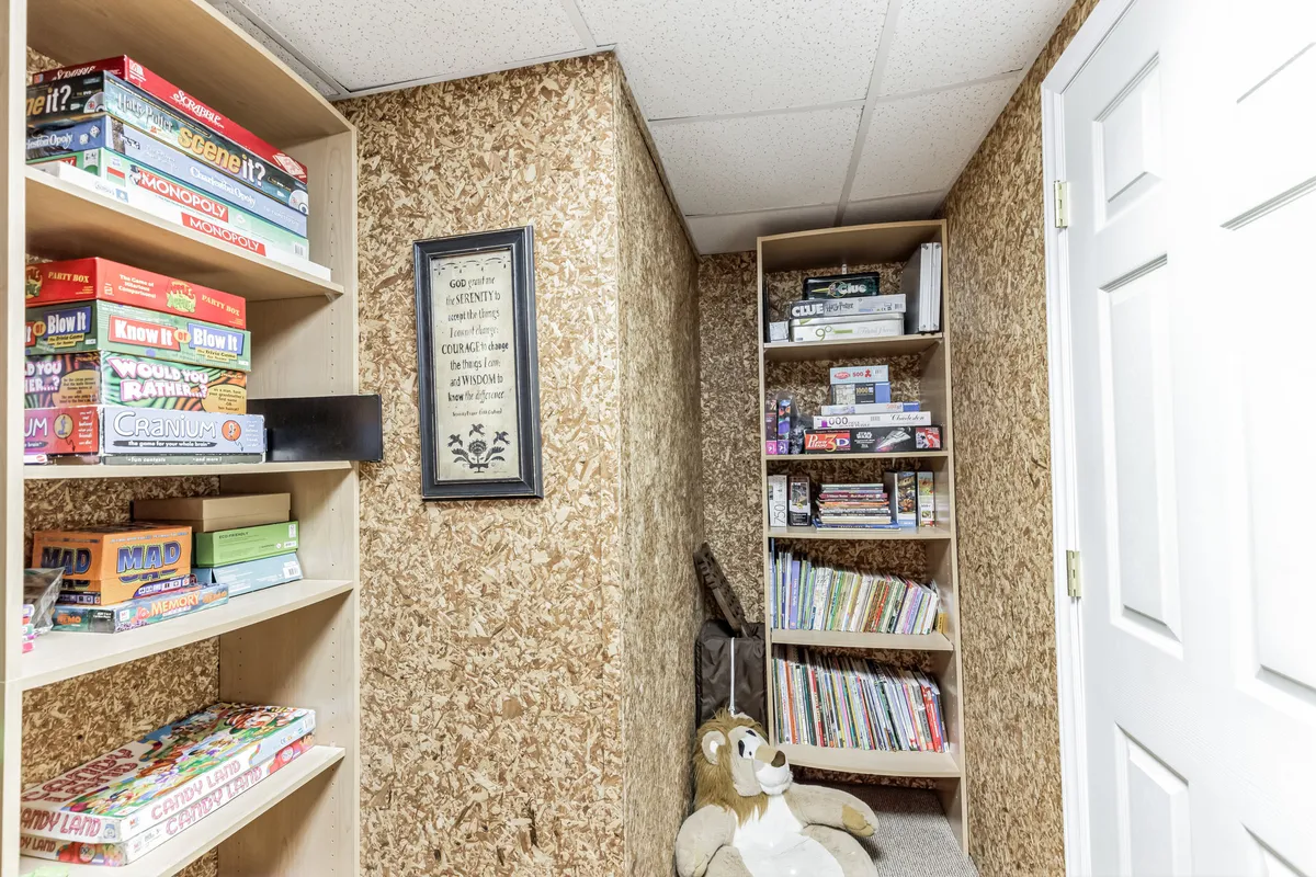 A playful, inviting game area with shelves lined with board games, a stuffed lion, and framed artwork. The space exudes nostalgia and fun, designed for family gatherings, storytelling, and building traditions.