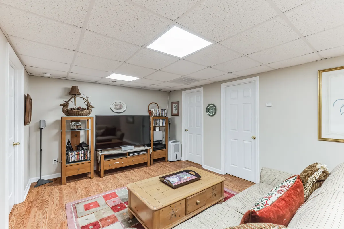 A cozy interior scene with a large sofa, coffee table, and television, accented by a decorative shelf. The space is arranged for comfortable gatherings and entertainment, ideal for movie nights, board games, and family storytelling.